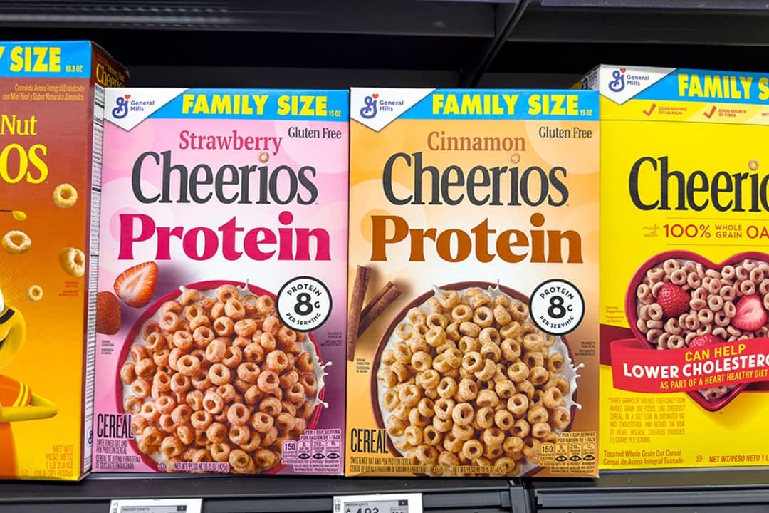Boxes of Cheerios Protein cereal arranged on a store shelf in a supermarket.